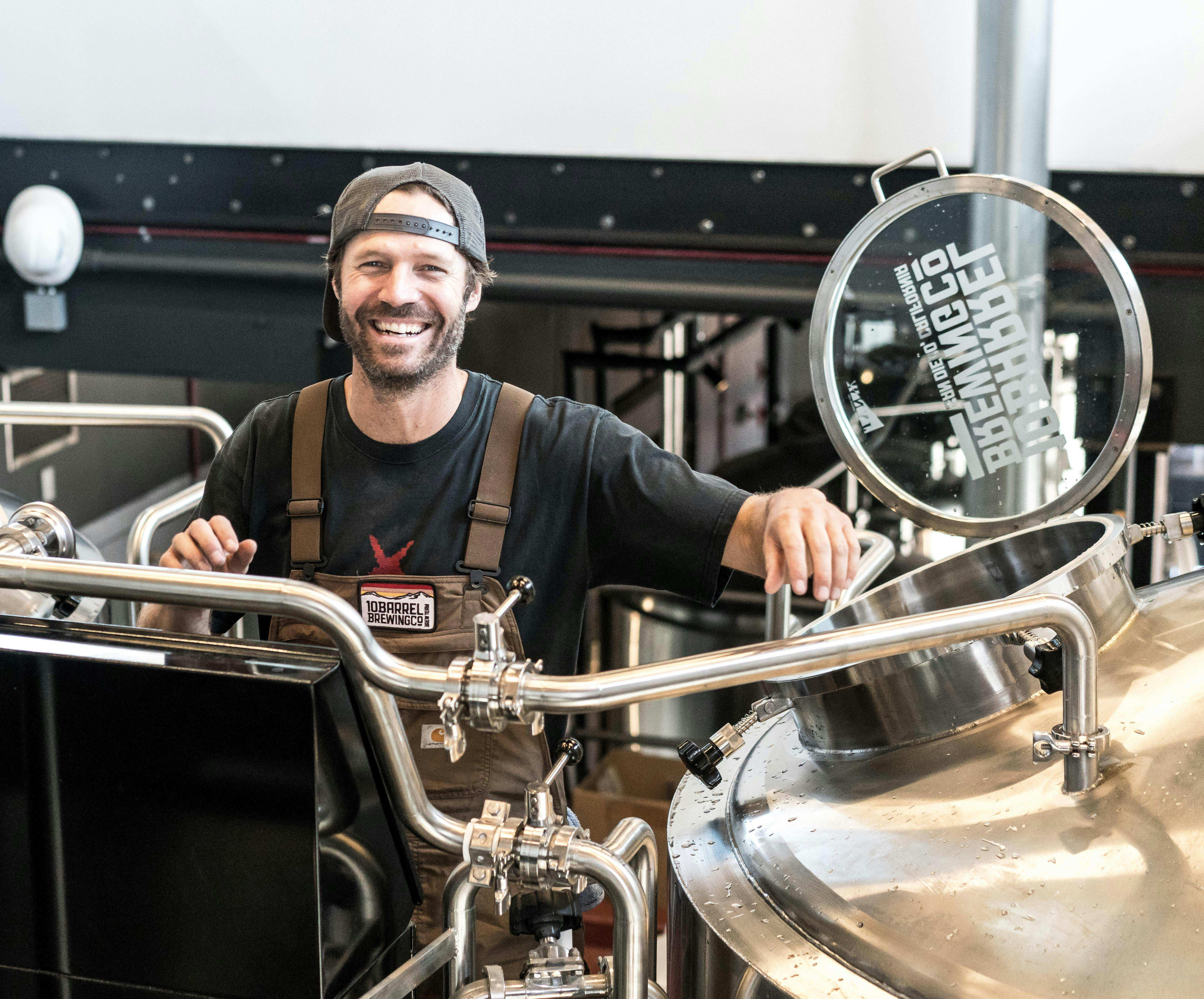 Mastro birraio sorridente al lavoro in un birrificio artigianale con attrezzature in acciaio inox