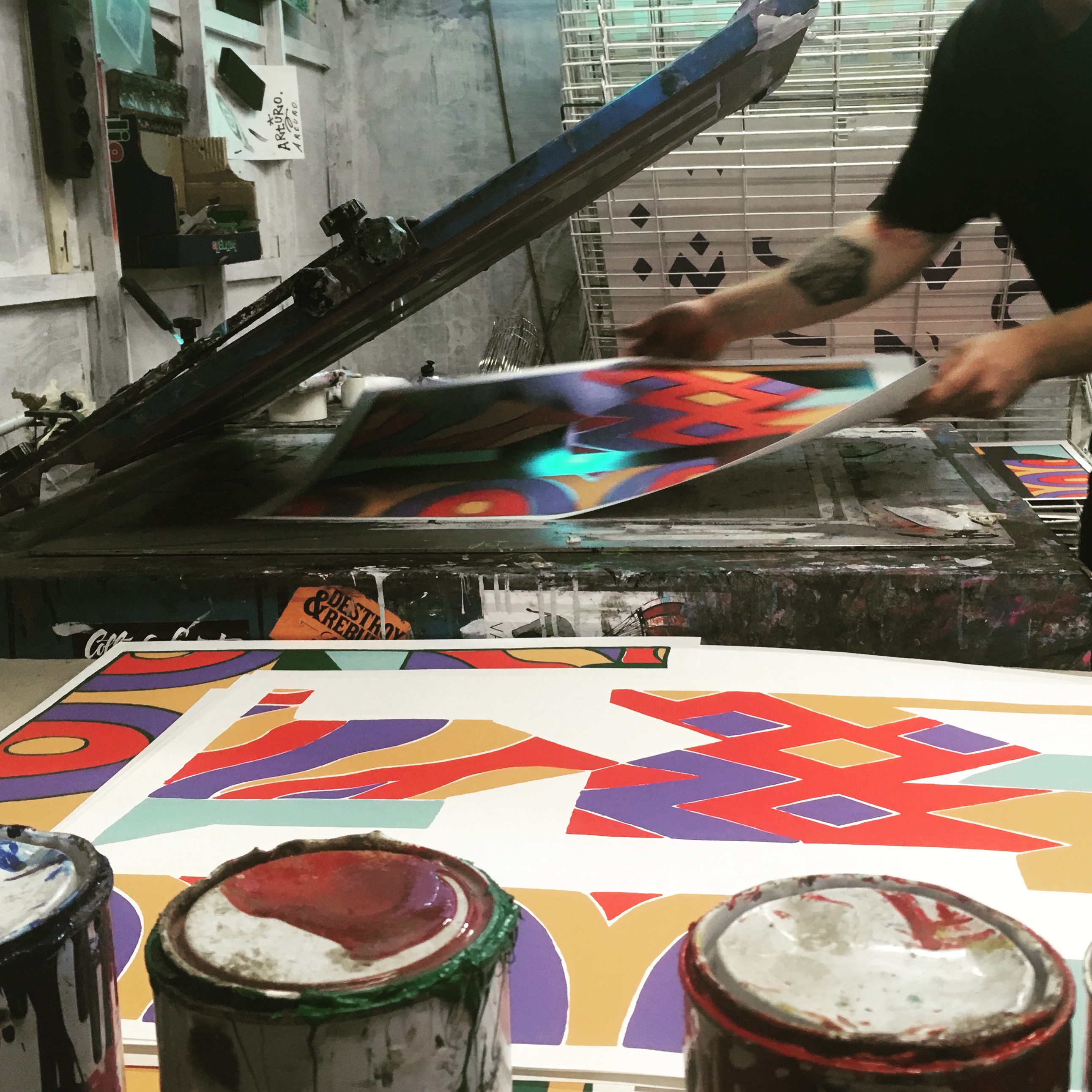 Workshop serigrafico con stampe colorate geometriche e serigrafo al lavoro