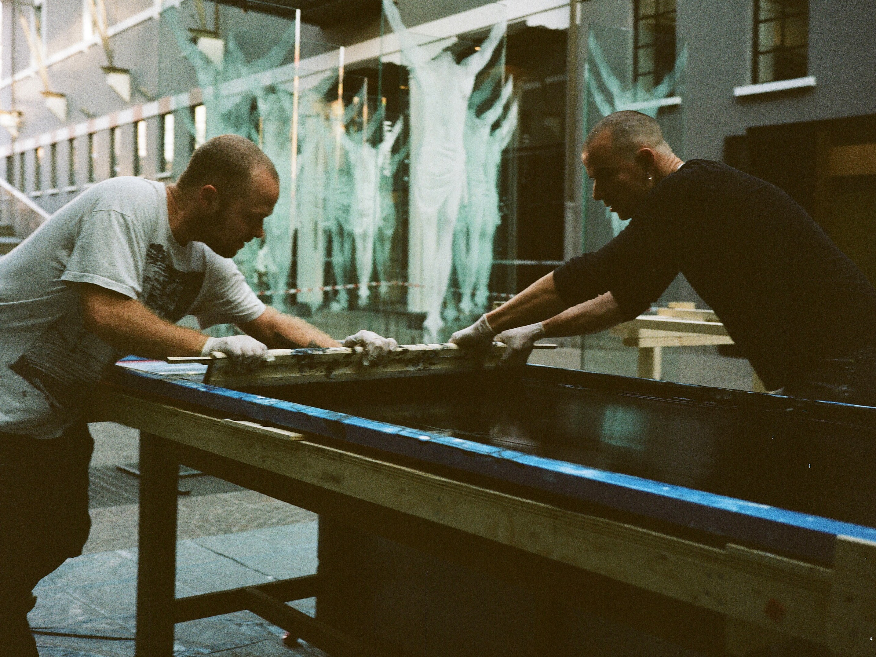 Artigiani al lavoro nel laboratorio di serigrafia con stampe che si asciugano
